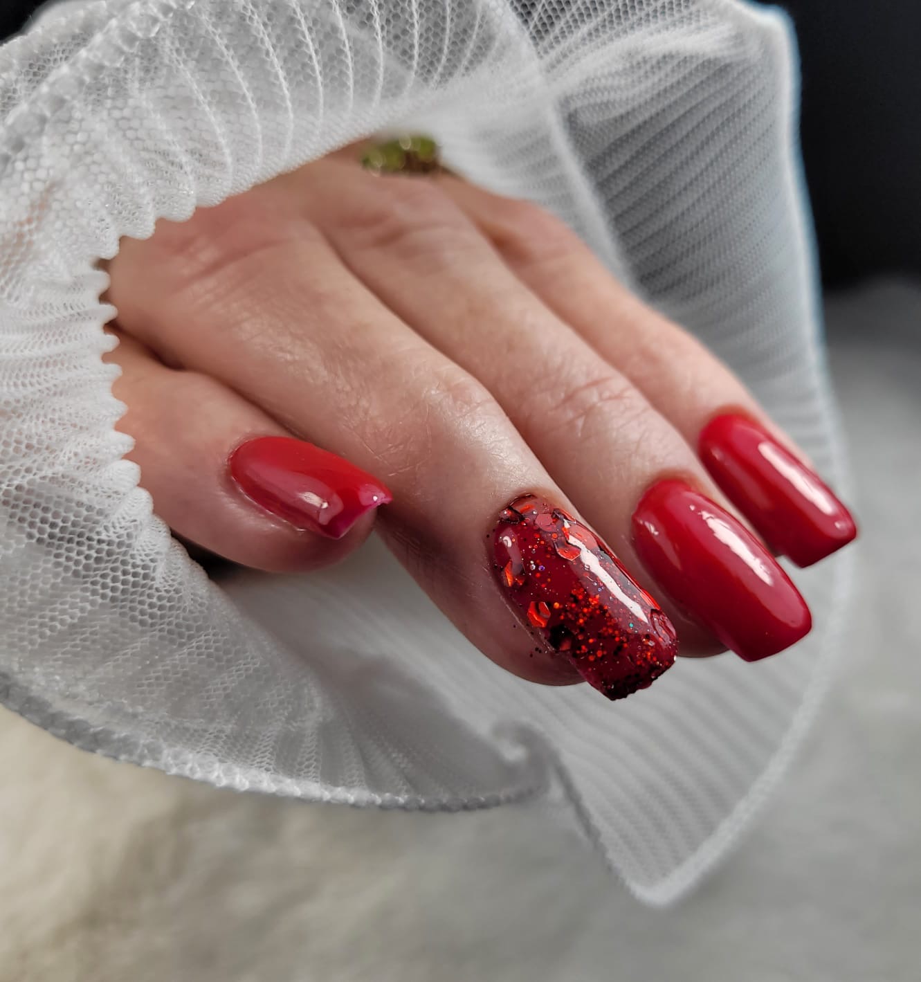 Rode nagels met een sprankelend accent op de ringvinger